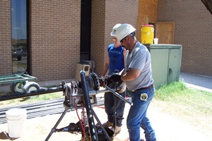 Plumbers cutting & threading pipe for gas line on roof