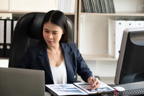 Female working on Laptop with Banking and Finance Documents