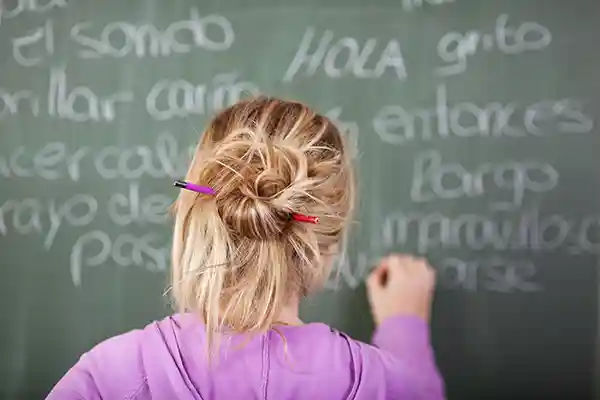 Young woman at green chalk board writing in Spanish
