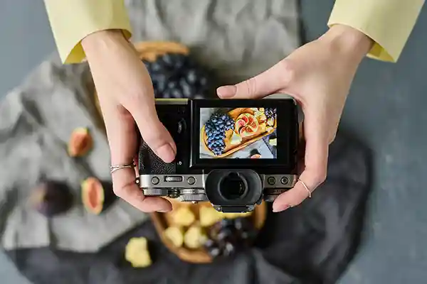Woman's hands holding camera showing the backside of digital version