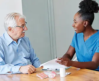 Female medication aide showing a prescription senior man