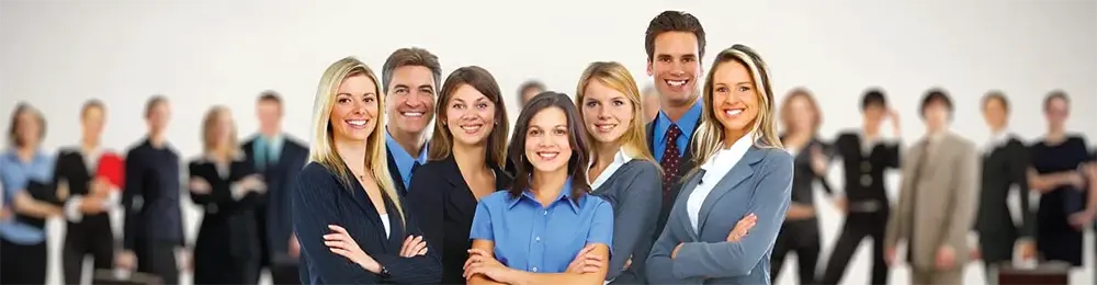 A group of diverse business professionals stand together smiling in an office setting