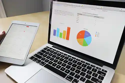 The image displays a laptop showing various data visualizations, along with a tablet next to it