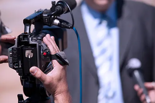 Journalist interviewing man on camera for TV.