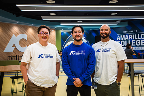 Three Amarillo College Career Services employees smiling for the camera in front of the college logo in the Enrollment Center