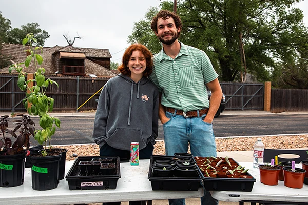 Two students smiling and posing with their plants at the annual Plant Sale
