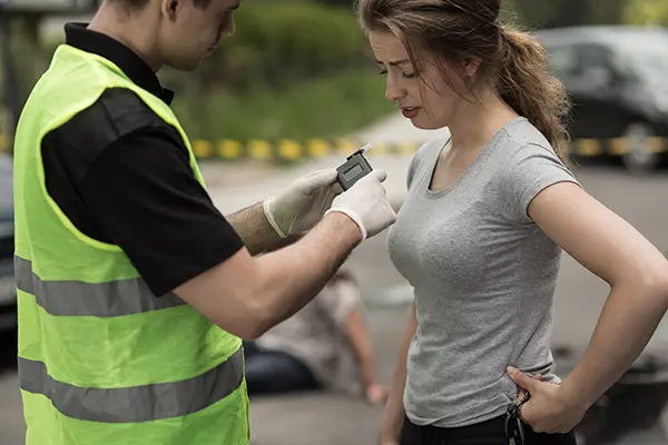 Image depicts photo of policeman and female accident perpetrator during breathalyzer test