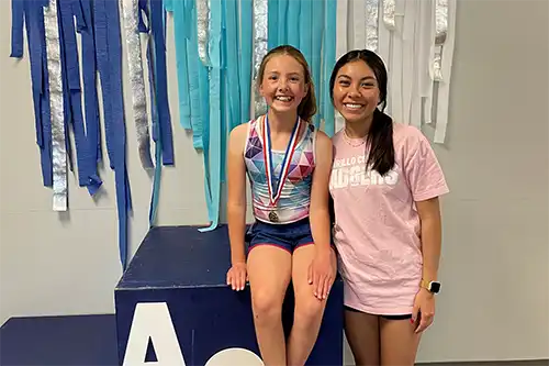 Fifth slide AC gymnastics instructor next to seated student